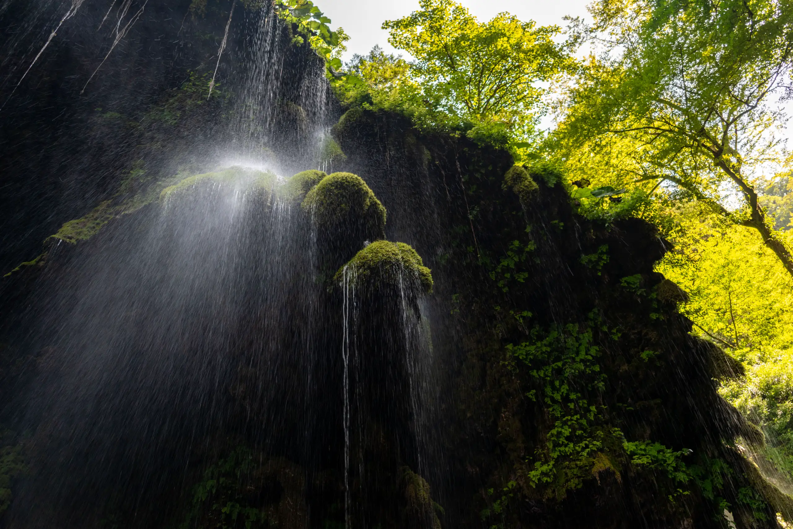 A low-angle shot of water cascading over mossy rock walls surrounded by dense green forest foliage at Behesht Baran Waterfall in Gorgan, Iran. Photograph by Mohammad Ataei.