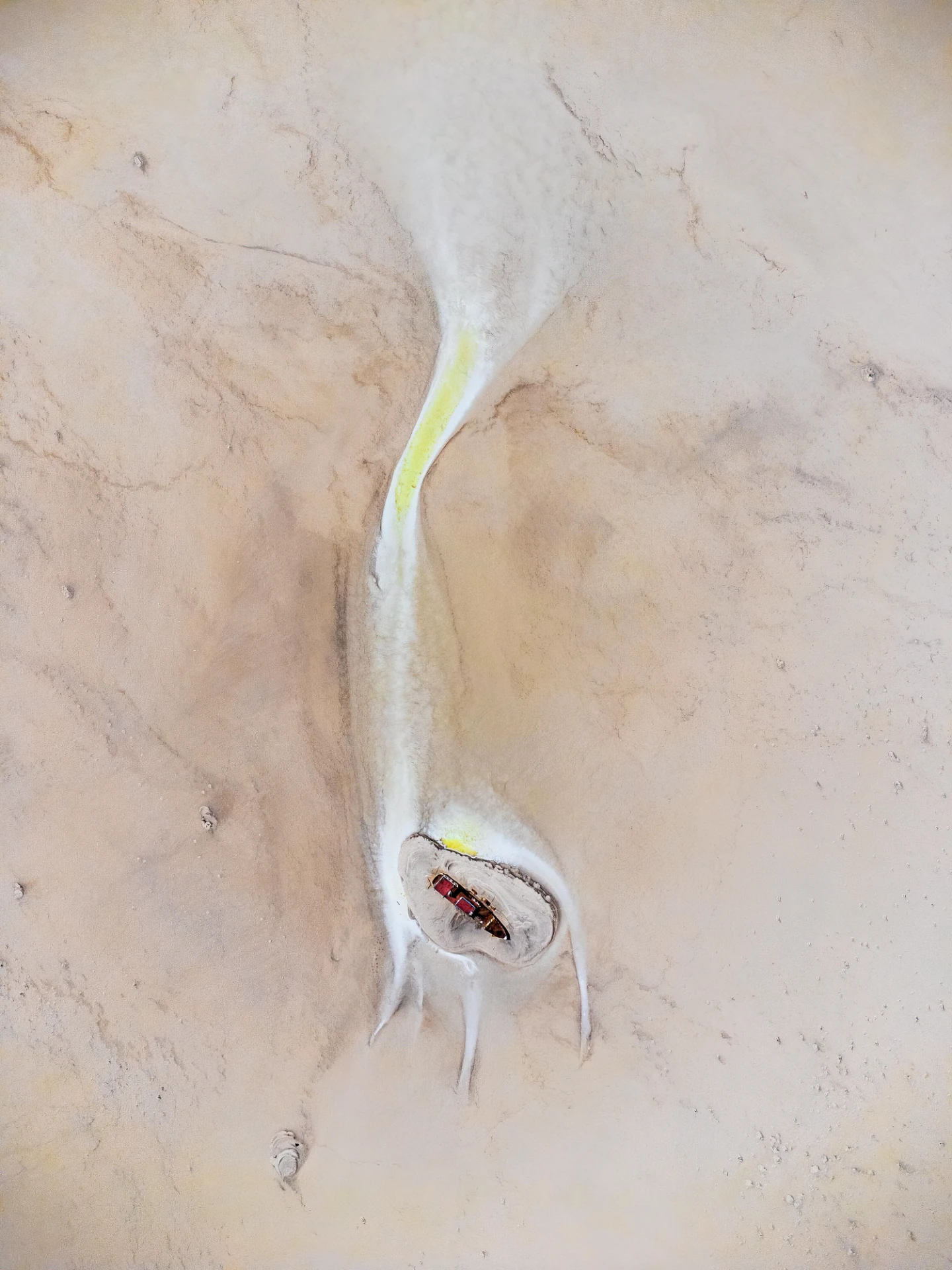 A vertical aerial view from 500 meters showing a reddish ship grounded on a circular salt formation in the pale expanse of Lake Urmia. Photograph by Mohammad Ataei.