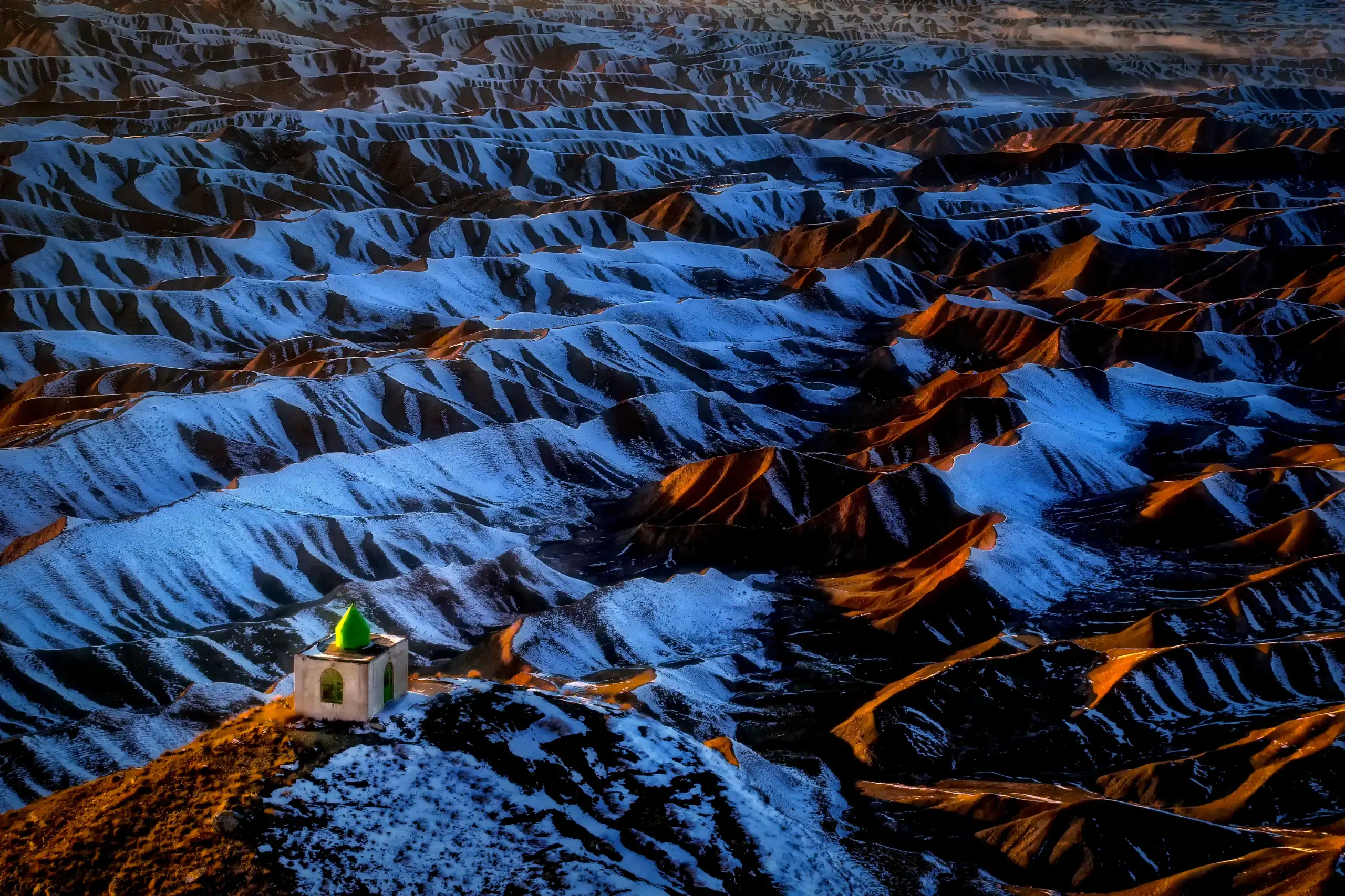 {"en":"The historic Khaled Nabi Shrine, a modest white structure with a green dome, overlooks the snow-covered 'Thousand Valleys' badlands at sunset in Kalaleh, Golestan Province, Iran. Photograph by Mohammad Ataei.","fa":"زیارتگاه تاریخی خالد نبی، بنایی سپید و ساده با گنبدی سبز، در غروب زمستانی بر تپهماهورهای برفی «هزار دره» در کلاله، استان گلستان، ایران مشرف است، عکس از محمد عطایی."}